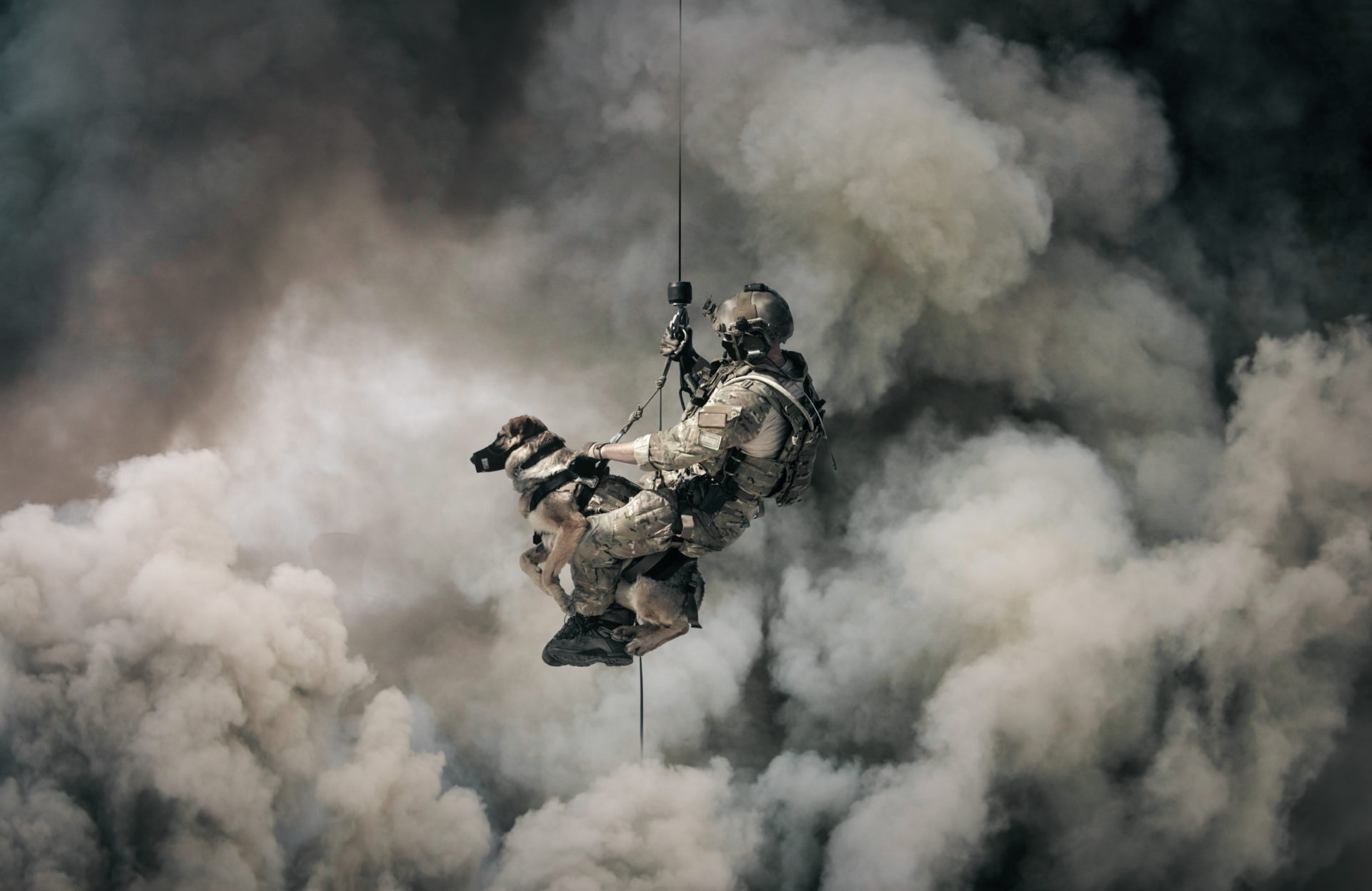 U.S. military personnel rappelling from a helicopter into smoke.